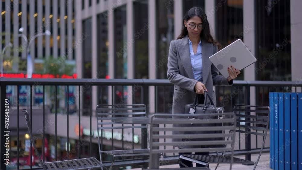 South Asian female entrepreneur in optical spectacles sitting in public place with good internet connection and using modern touch pad for digital marketing while receiving cell call for consultation South Asian female entrepreneur in optical spectacles sitting in public place with good internet connection and using modern touch pad for digital marketing while receiving cell call for consultation