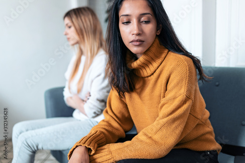 Foto Two upset friends not talking to each other after fight on the sofa at home