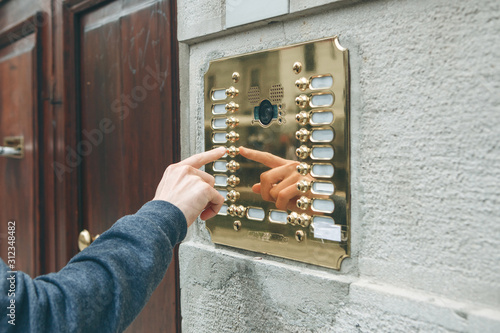 Foto A male hand presses a doorphone button for access inside.