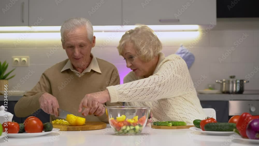 Elderly couple cutting fresh organic vegetables in kitchen, living healthy life Elderly couple cutting fresh organic vegetables in kitchen, living healthy life