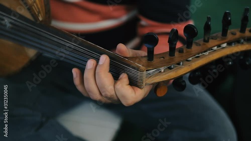 A musician playing a lute (a plucked string instrument with a curved neck). Handheld detail shot of the player's hands. photo