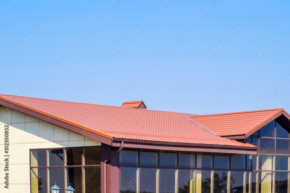 building with yellow walls and a red-brown roof. Modern materials of finish and roofing.