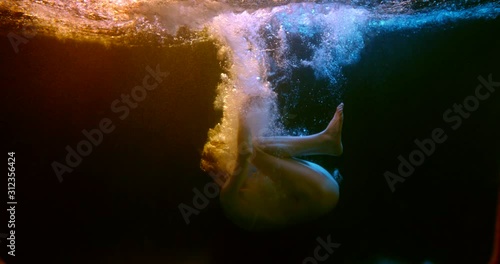 Pathetically plump slender girl under the water in the fetal position in her underwear dark neon lighting photo