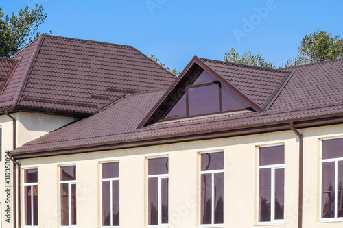 House with plastic windows and roof of corrugated sheet. Roofing of metal profile wavy shape on the house with plastic windows