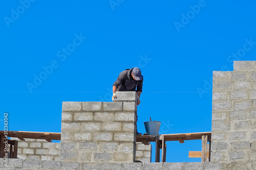 Wallpaper Mural The builder builds the wall of the house from the cinder block. Worker at the construction site. Torontodigital.ca