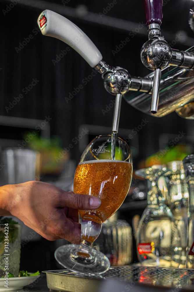 Hand of bartender pouring a large lager beer in tap. males hands. Pouring beer for client