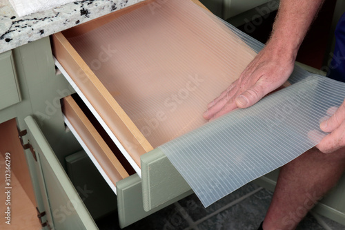 Photo Caucasian Male Hands Placing Plastic Drawer Liner in a Bathroom