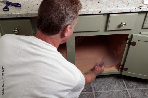 Adult Male Placing Clear Shelf Liner in a Bathroom Cabinet