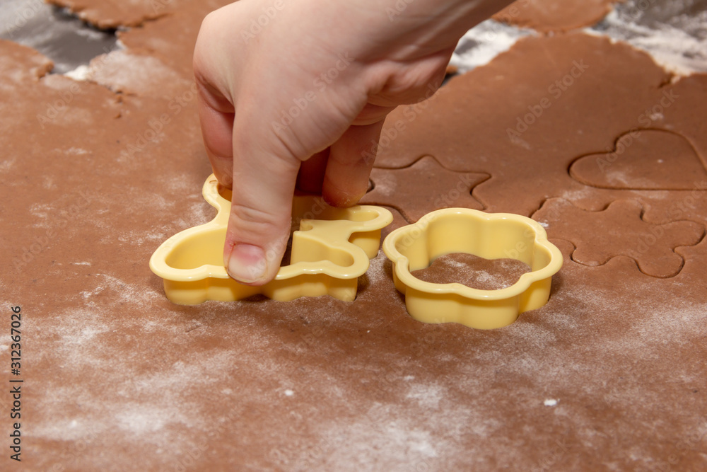 Cutting figures from the dough using special stencils for making ginger Christmas cookies. Children's hands close-up. Home, family prepare for the holidays concept Cutting figures from the dough using special stencils for making ginger Christmas cookies. Children's hands close-up. Home, family prepare for the holidays concept