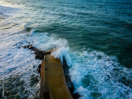 Aerial view of a pier with rocks and rocks on the sea. Pizzo Calabro pier, panoramic view from above. Broken pier, force of the sea. Power of Waves. Natural disasters, climate change. Calabria. Italy © Naeblys
