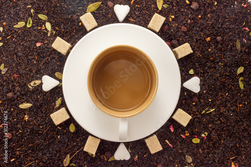 eternity mug on white circle saucer with brown and white pieces sugar on black leaf tea background