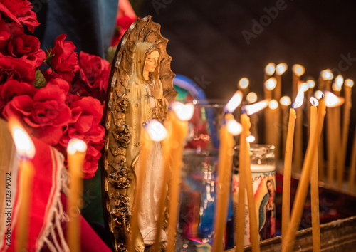 Small statue figures of the Virgin Mary and candles are lit at a church altar