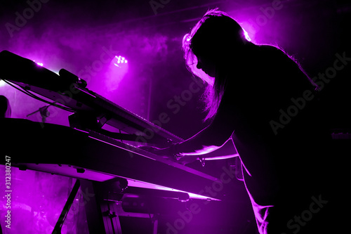 Silhouette of girl playing keyboards during concert