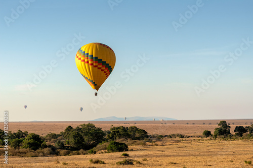Brightly colored balloon flying over the savanna in the Maasai Mara, Kenya. 