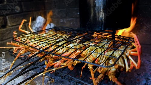 Barbecuing crayfish on open fire, lifting grid to expose outer shell and dripping sauce photo
