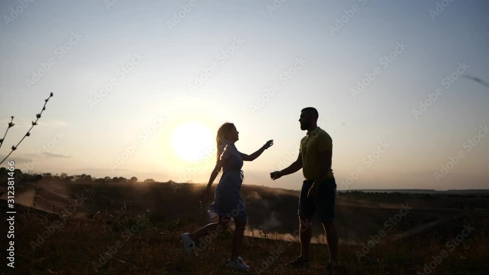 Young girl runs in slow motion toward a bearded young man and kisses him. Couple in rural landscape at breathtaking golden sunset. Young girl runs in slow motion toward a bearded young man and kisses him. Couple in rural landscape at breathtaking golden sunset.
