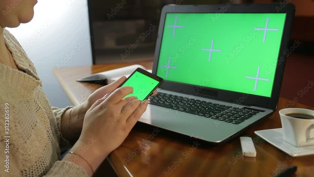 A woman in the evening at the office at the table is looking for information in her smartphone A woman in the evening at the office at the table is looking for information in her smartphone