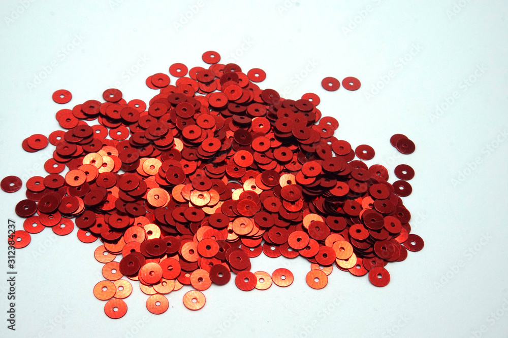 Red sequins on white background. Sewing and decorating accessories used for embellishment of dresses. Copy space. Red sequins on white background. Sewing and decorating accessories used for embellishment of dresses. Copy space.