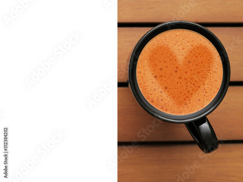 Black coffee mug on a wooden table. Art sign on heart the foam, White copy space for text. Top view. Warm tones.