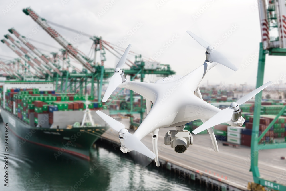 Unmanned Aircraft System Quadcopter Drone In The Air Near Large Shipping Vessel and Dock with Crates