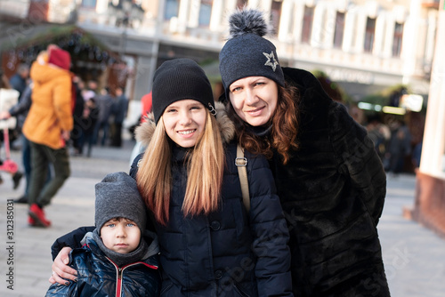 Authentic portrait of a mom with two kids vacationing in town together, returning home after church. The boy is sad because winter but there is no snow