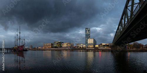 Überseestadt in Bremen, Germany with reflections on the river Weser and lights in the office buildings during blue houer with cloudy sky photo