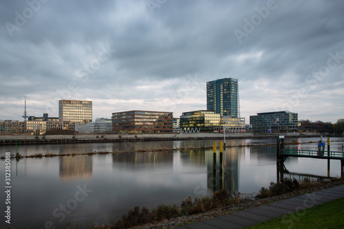  berseestadt in Bremen  Germany with reflections on the river Weser and lights in the office buildings during blue houer with cloudy sky