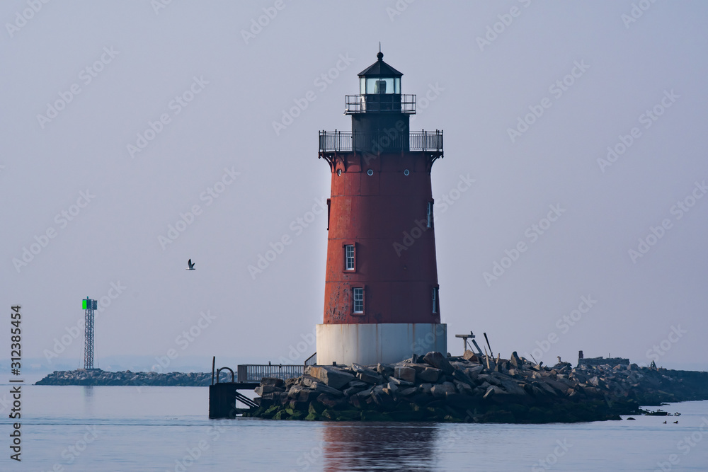 A red lighthouse on the bay in Delaware during twilight 