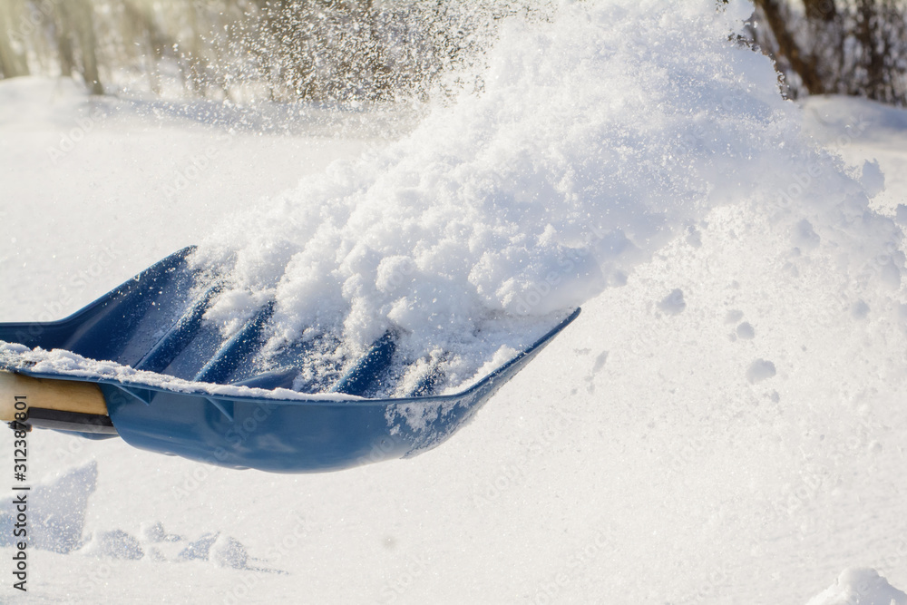 Photo in action. Throwing snow with shovel while cleaning backyard after a heavy snow Photo in action. Throwing snow with shovel while cleaning backyard after a heavy snow