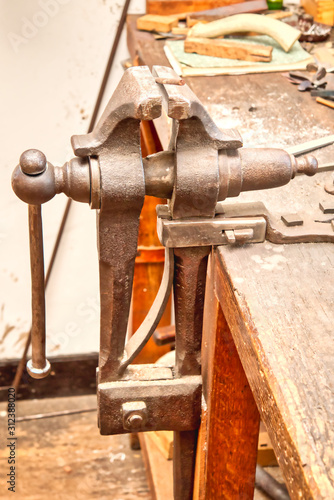 A closeup of an antique bench vise on a bench.