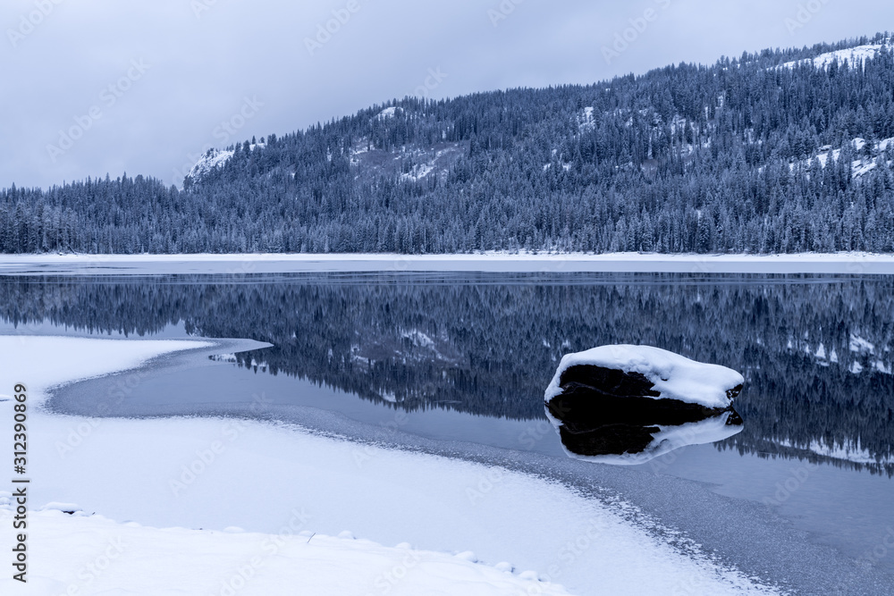 Fototapeta premium Upper Payette Lake winter cold snow and ice with dark forest