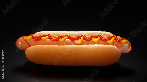 фотографія Classic hot dog with ketchup and mustard on a black background.