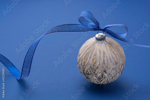 Christmas bauble with blue ribbon, isolated over blue background. Classic blue abstract background. Copy space. photo