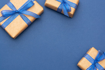 Christmas or birthday presents frame or border. Craft paper wrapped gift boxes on blue background, flat lay. Copy space.