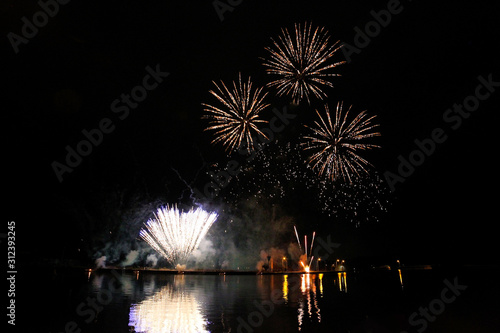 Feuerwerk am Nachthimmel mit Spiegelungen im Wasser photo