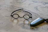 Pair of round magnifying spectacles on top of old sea faring map