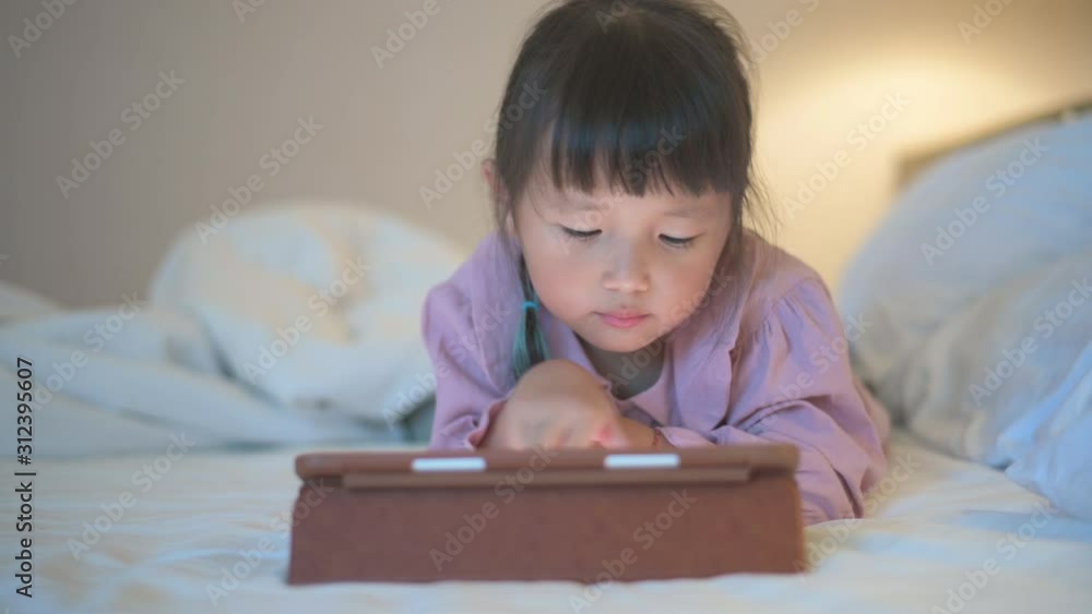 liitle girl are watching tablets in bed at night, children using phones or playing tablet games, children using games with addiction and cartoon concepts liitle girl are watching tablets in bed at night, children using phones or playing tablet games, children using games with addiction and cartoon concepts