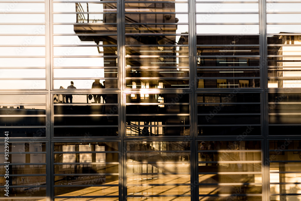 Reflection of people on a modern glass facade at sunset Reflection of people on a modern glass facade at sunset