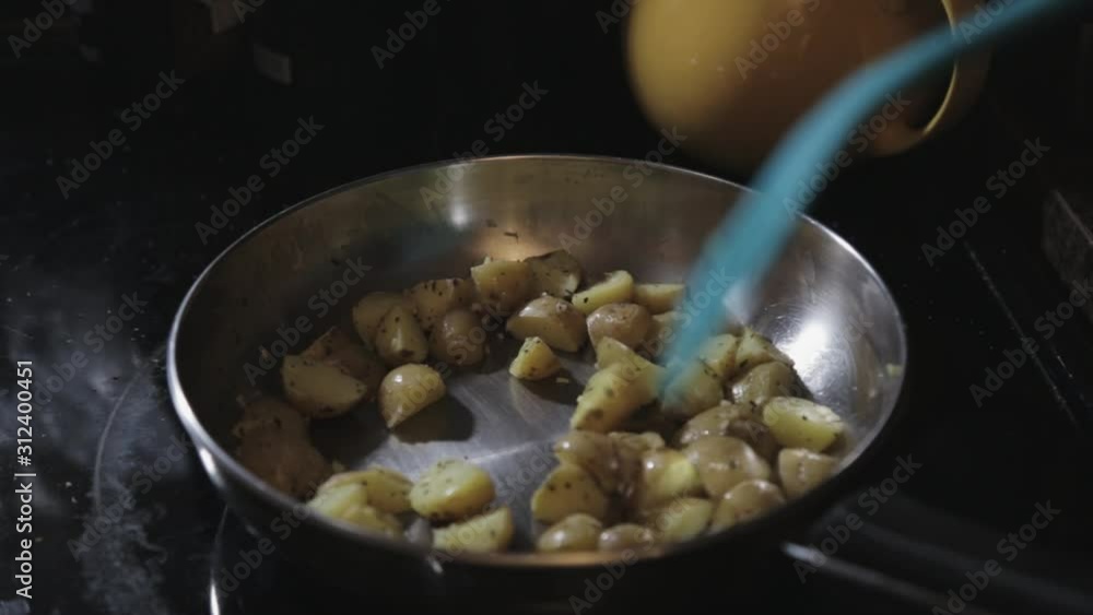 Cooking A Delicious Sliced Of Potatoes In A Pan With Basil Leaf - Close Up Shot