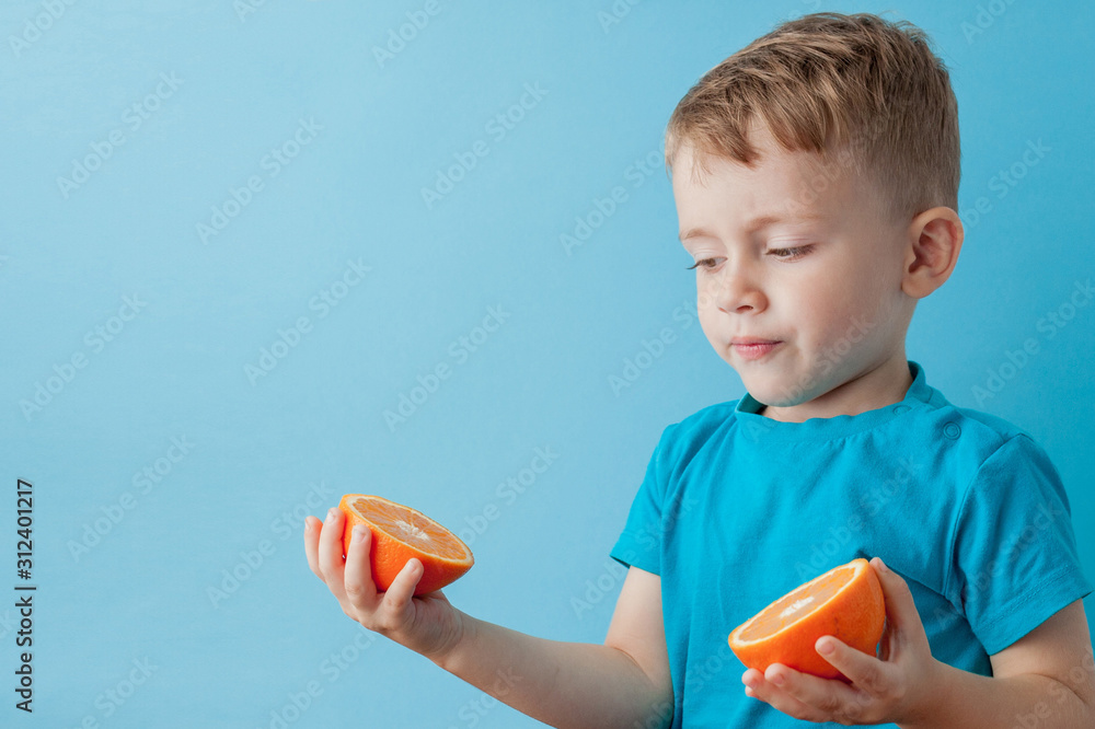 Little Boy Holding an Orange in his hands on blue background, diet and exercise for good health concept Little Boy Holding an Orange in his hands on blue background, diet and exercise for good health concept