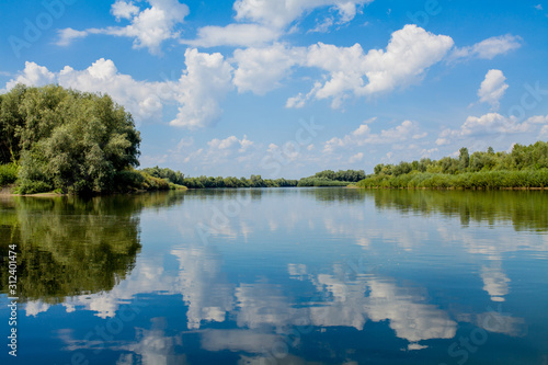 Blue beautiful sky against the background of the river. Clouds are displayed in calm water. On the horizon  the green bank of the Dniester  place for fishing