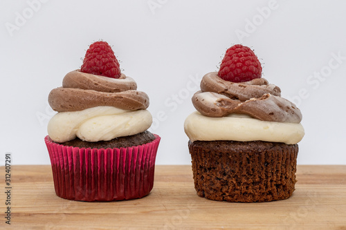 chocolate cupcake with frosting and raspberry garnish on wodden board
