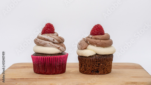 chocolate cupcake with frosting and raspberry garnish on wodden board