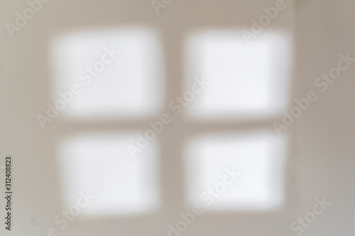 the out of focus abstract window cross shadow on the wall in the morning
