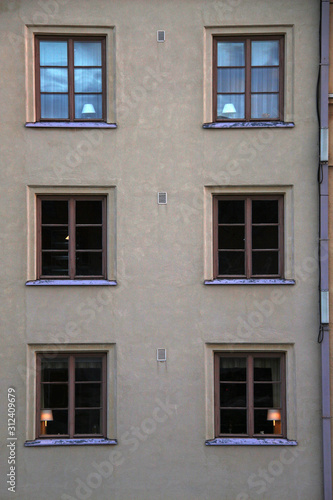 house facade with lamps with lampshades in windows and ventilation grills