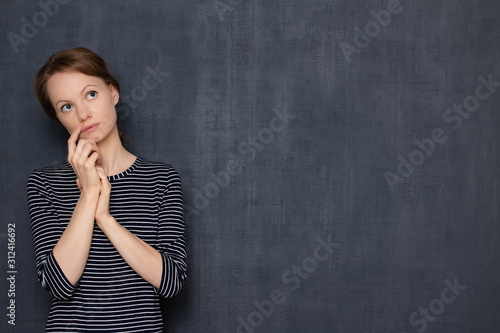 Portrait of focused pensive girl touching face with hand