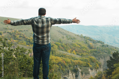 man with hands in the air stand on nature