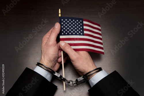 Valokuva Men's hands in handcuffs hold the American flag in their hands