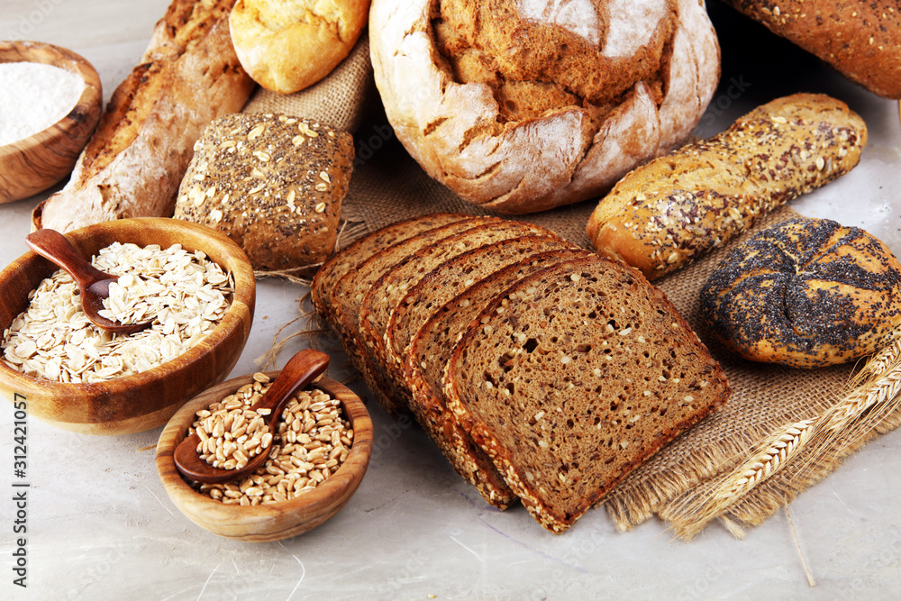 Assortment of baked bread and bread rolls and cutted bread on table background Assortment of baked bread and bread rolls and cutted bread on table background