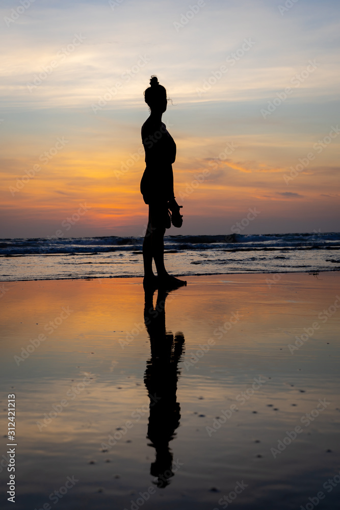 Silhouette of a girl standing in the water on a beach